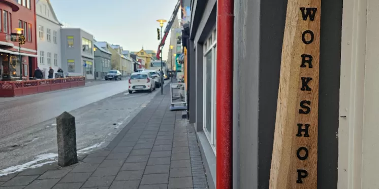 Stadtstraße mit bunten Gebäuden und einem Holzschild mit der Aufschrift „WORKSHOP“ 